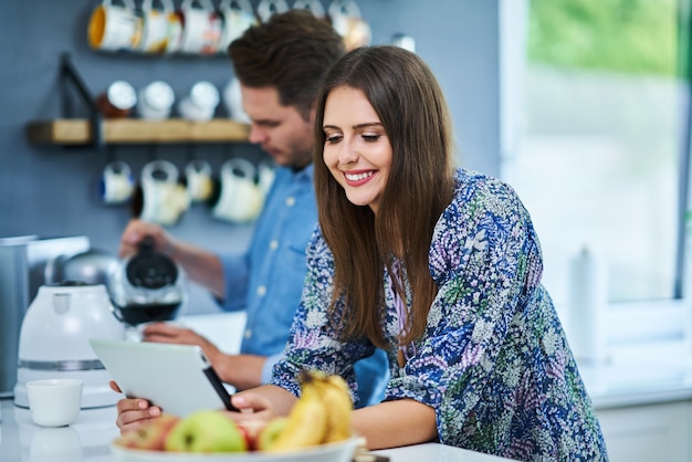 Pareja en la cocina de casa con tableta electrónica