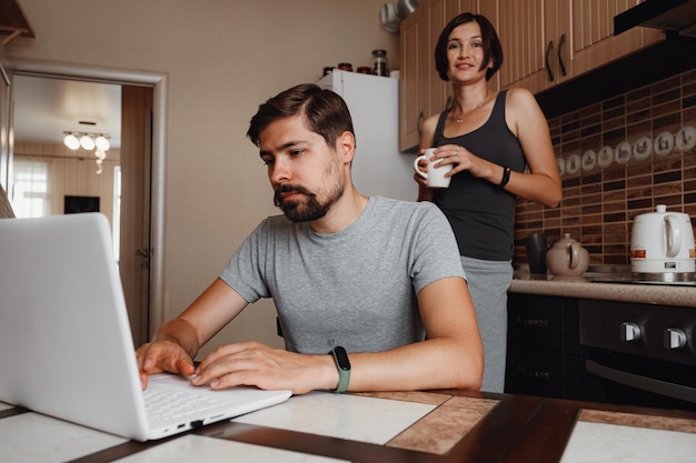 Pareja en la cocina leyendo noticias y usando una laptop