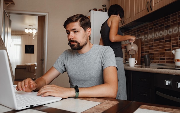 Pareja en la cocina leyendo noticias y usando una laptop