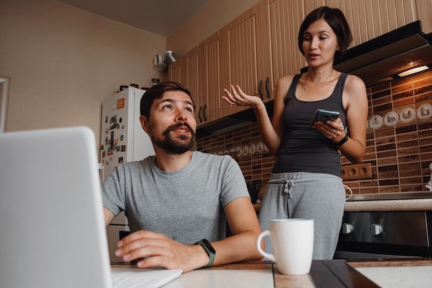 Pareja en la cocina leyendo noticias y usando una laptop