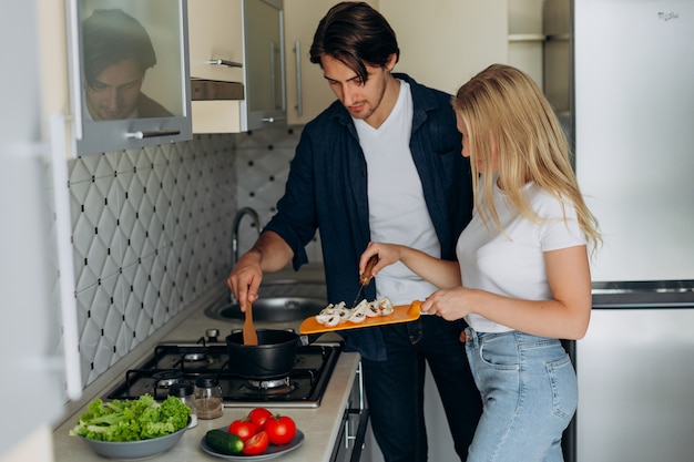 Pareja en la cocina durante preparó una comida sana. - Mujer sosteniendo un hongo