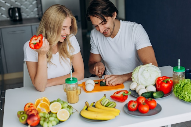 Pareja en la cocina sentado en la mesa con comida sana.