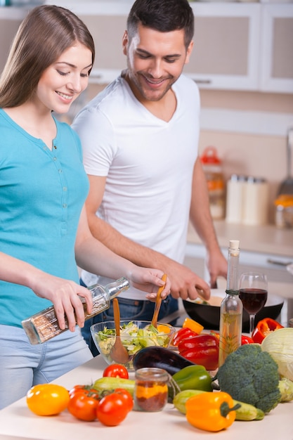 Pareja cocinando la cena. Feliz pareja joven cocinando la cena en la cocina