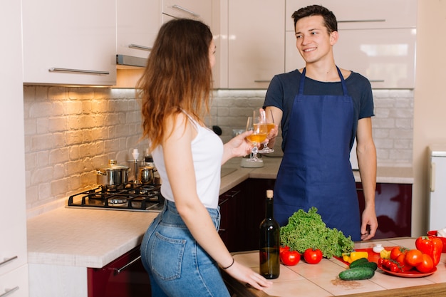 Pareja cocinando juntos y degustando vino.