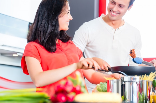 Pareja cocinando pasta en la cocina doméstica