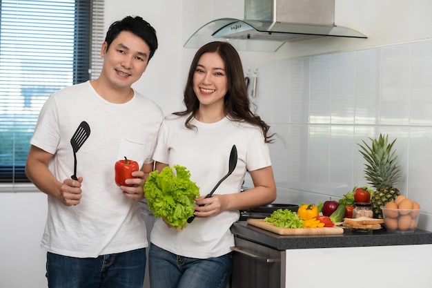 Pareja cocinando y preparando verduras en la cocina de casa