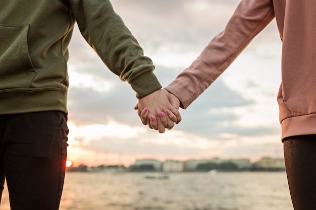 Pareja cogidos de la mano al aire libre en puesta de sol