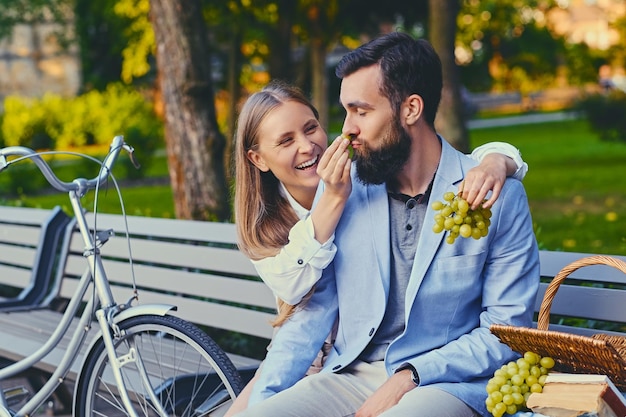 Una pareja come uva en un banco de un parque.