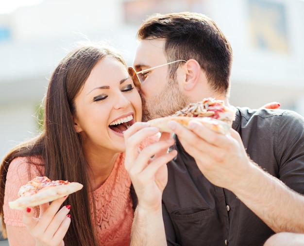 Pareja comiendo bocadillos de pizza al aire libre