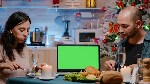 Pareja comiendo comida festiva viendo la pantalla verde horizontal