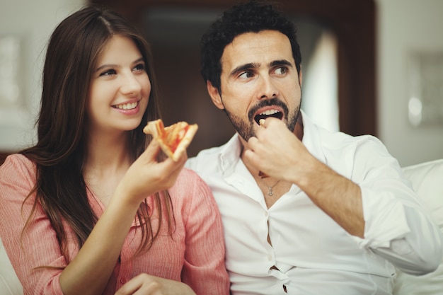 Pareja comiendo pizza y viendo la tele