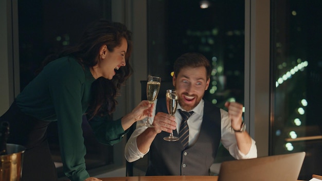 Una pareja de compañeros de trabajo bebiendo champán celebrando el éxito del negocio en la oficina