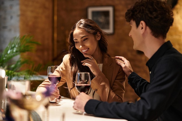 Una pareja comparte sonrisas y risas íntimas mientras beben vino en un encantador restaurante