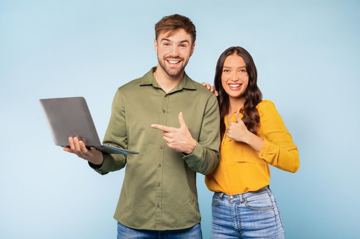 Pareja con computadora portátil apuntando a la computadora con fondo azul