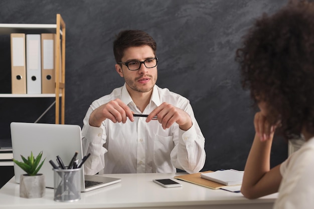 Pareja concentrada de jóvenes colegas que trabajan en la oficina moderna. Hombre serio hr entrevistar a candidata, espacio de copia