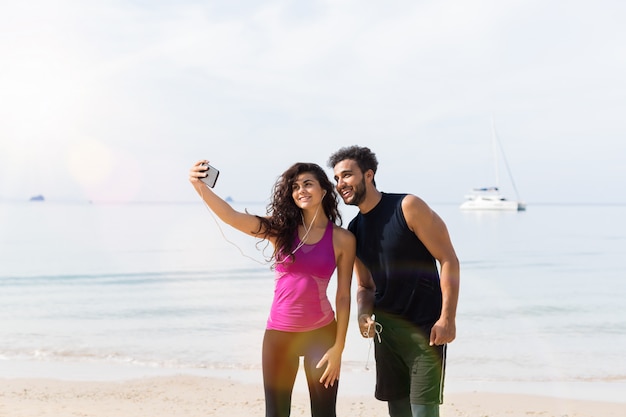 Foto pareja de corredores tomando fotos de selfie mientras corrían juntos en la playa