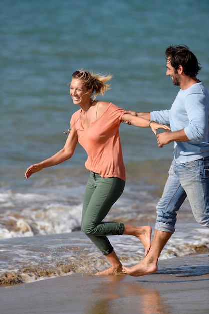 Pareja corriendo y divirtiéndose en la playa