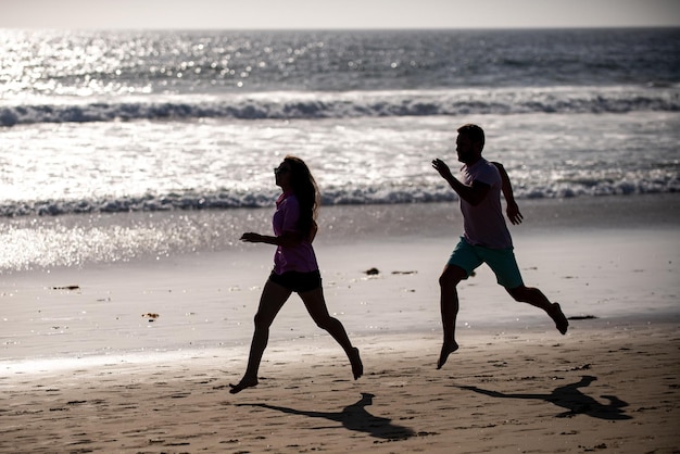 Pareja corriendo en la playa. Corredores deportivos trotar en la playa haciendo ejercicio. Concepto de ejercicio físico al aire libre.