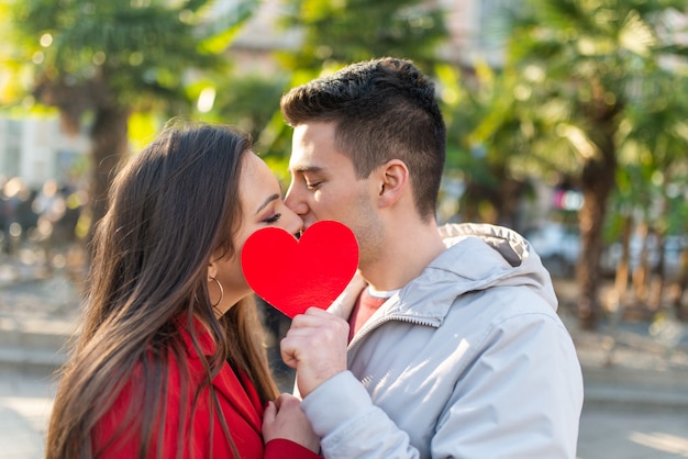 Pareja cubriendo su beso con un corazón