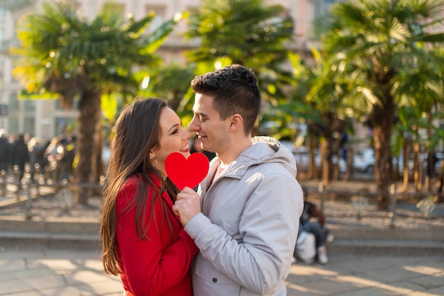 Pareja cubriendo su beso con un corazón