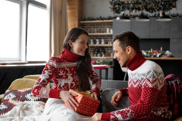 Foto pareja dándose regalos de navidad