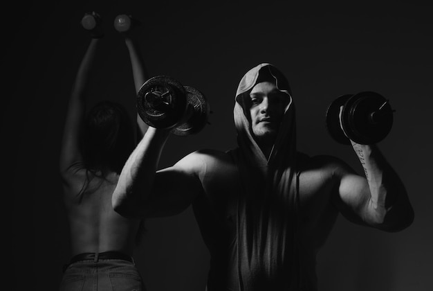 Pareja de deporte sexy haciendo ejercicio con una chica sexy delgada y saludable con mancuernas con un hombre musculoso fuerte trabajando