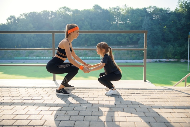 Pareja deportiva haciendo ejercicio de salto durante el entrenamiento físico en el estadio al aire libre