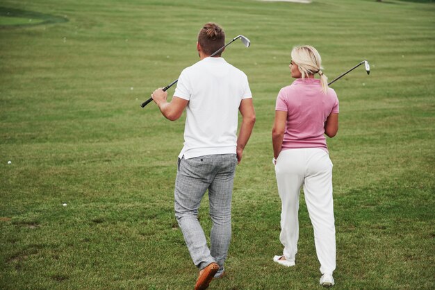 Pareja deportiva jugando al golf en un campo de golf, se paran al siguiente hoyo