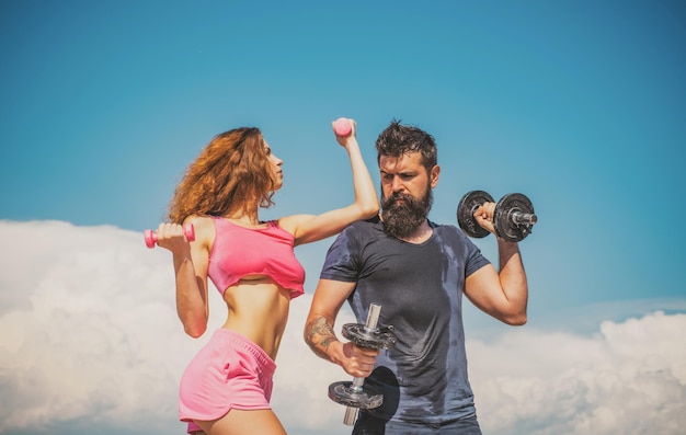 Pareja deportiva con pesas al aire libre pareja haciendo ejercicio con pesas en el gimnasio al aire libre en el cielo