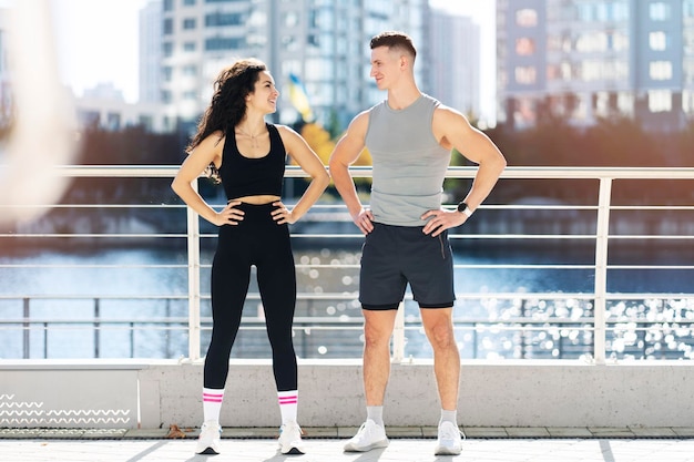 Pareja deportiva positiva posando después del deporte juntos en la calle