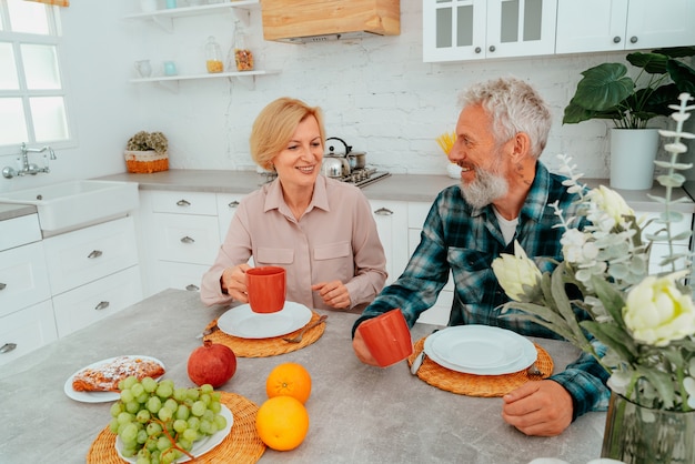 Pareja desayuna en casa con café y frutas.