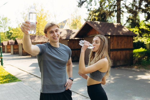 Foto pareja descansando después de entrenar y beber agua en el parque el concepto de un estilo de vida saludable