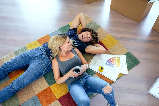 Pareja descansando sobre la alfombra de su nueva casa