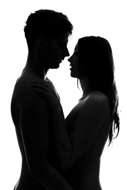 Una pareja desnuda abrazándose mientras están de pie contra un fondo blanco