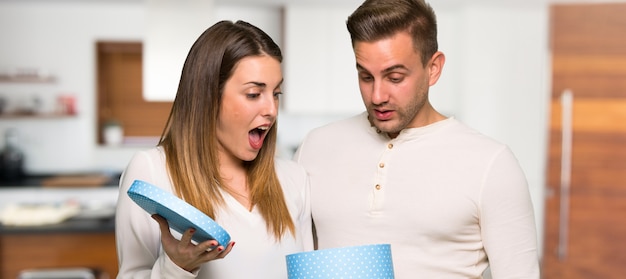 Pareja en el día de San Valentín con caja de regalo en las manos en una casa