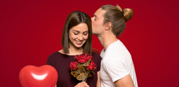 Pareja en el día de San Valentín con flores sobre fondo rojo