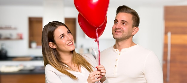 Pareja en el día de San Valentín con globos con forma de corazón en una casa