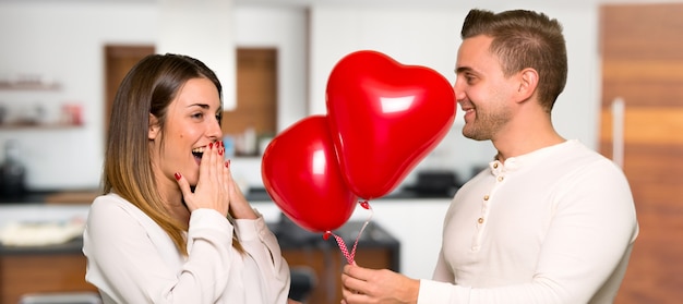 Pareja en el día de San Valentín con globos con forma de corazón en una casa