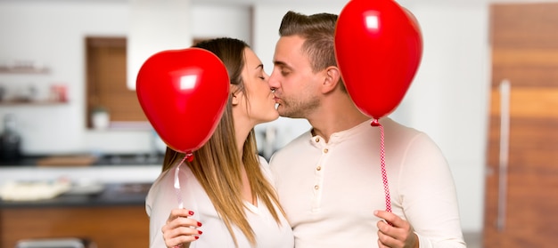 Pareja en el día de San Valentín con globos con forma de corazón en una casa