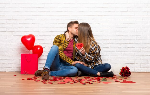 Pareja en el día de San Valentín en el interior sosteniendo un símbolo de corazón y besos