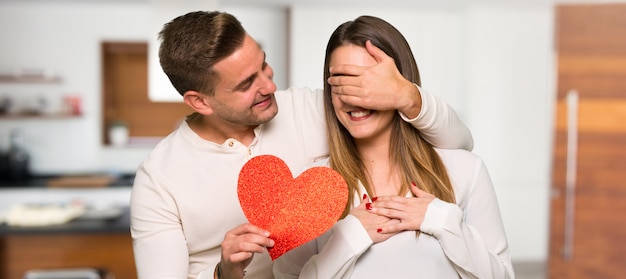 Pareja en el día de San Valentín con un símbolo de corazón en una casa