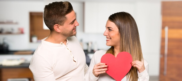 Pareja en el día de San Valentín con un símbolo de corazón en una casa