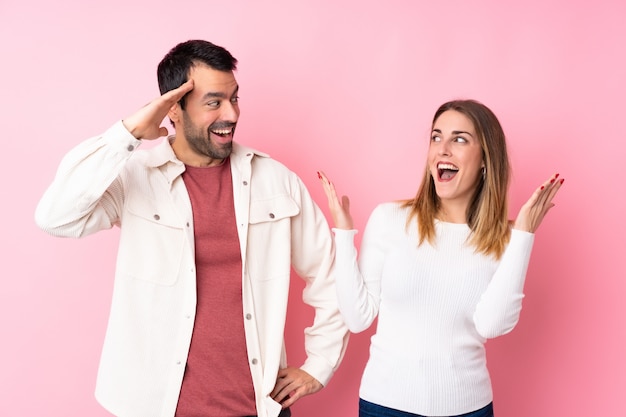 Pareja en el Día de San Valentín sobre pared rosa aislada con sorpresa y expresión facial conmocionada