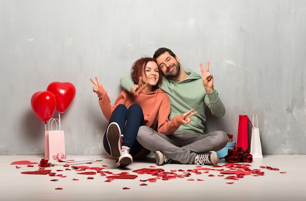 Pareja en el día de San Valentín sonriendo y mostrando el signo de la victoria