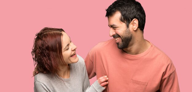 Pareja en el día de San Valentín sonriendo mucho sobre fondo rosa aislado