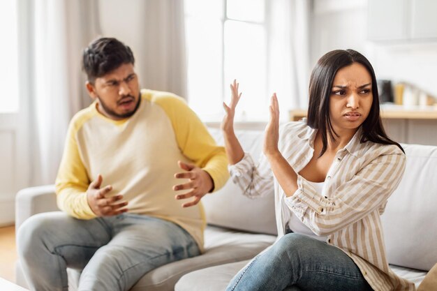 Una pareja discutiendo en el sofá en casa.