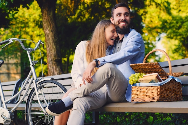 Una pareja disfruta de un picnic en un banco de un parque.