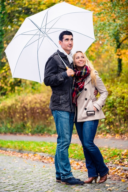 Pareja disfrutando día de otoño paseando a pesar de la lluvia.