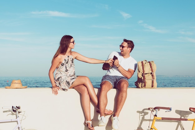 Una pareja disfrutando mientras se sienta en una pared de retención junto al mar contra el cielo