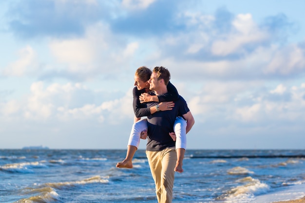 Pareja disfrutando de la romántica puesta de sol en la playa del mar del norte alemán